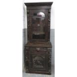 A Victorian carved oak cabinet, the upper section with glazed door enclosing three shelves, the base