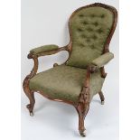 A Victorian walnut framed upholstered open armchair with foliate carved back & arm supports, in