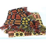 A woven Welsh wool blanket in geometric orange/yellow/black design with reverse pattern to each side