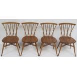 A set of four Ercol blonde wood stick back chairs with elm seats