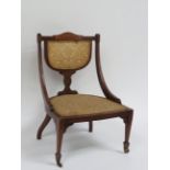 A late Victorian inlaid mahogany nursing chair on brass castors