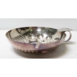 A decorative silver metal tasting bowl with thumb support to one side, 14cm diameter