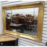 Modern gilt framed mirror, rectangular with floral decoration, the mirror with bevelled edge,