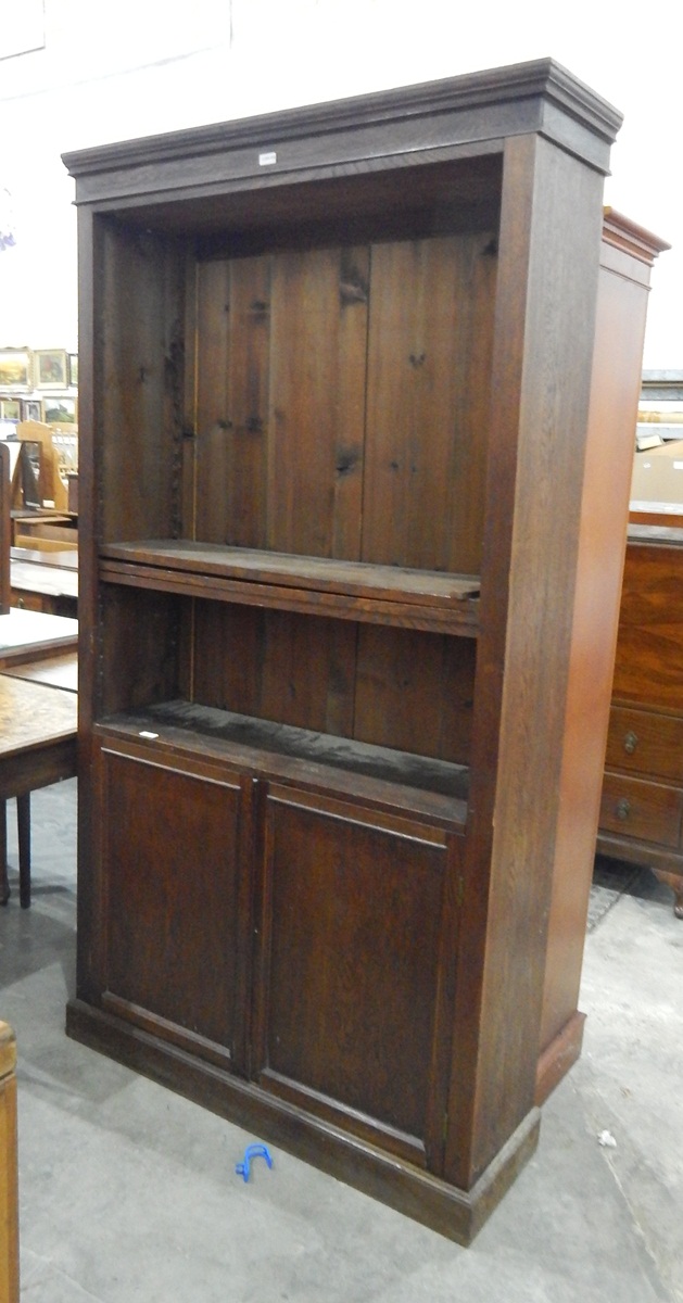 Oak bookcase fitted with open adjustable shelves over two cupboard doors, on plinth base,