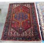 Eastern wool rug with blue hooked octagonal arabesque to the cherry red field and having ivory