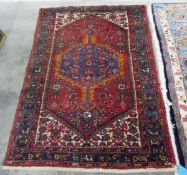 Eastern wool rug with blue hooked octagonal arabesque to the cherry red field and having ivory