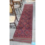 Meshwani wool runner, cherry red ground with three rows of lozenge medallions, chevron border,