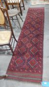 Meshwani wool runner, cherry red ground with three rows of lozenge medallions, chevron border,