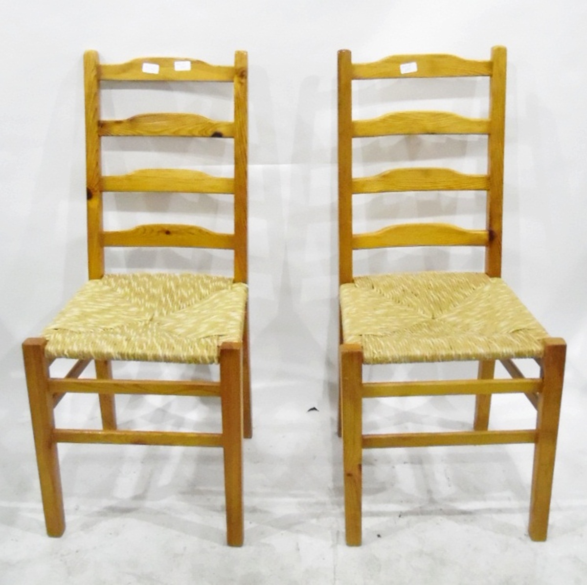 Three modern pine kitchen chairs with ladder backs and rush seats