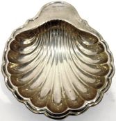 George V silver shell-shaped butter dish on three ball feet,