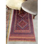 A Persian wool runner in red with blue decoration,