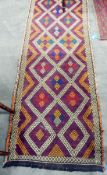 A middle Eastern wool runner in a geometric design in cream, purple, orange and blue,