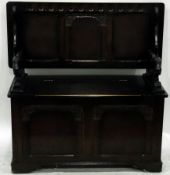 Stained oak monk's bench with rising top and box seat, carved panels, on bracket feet,