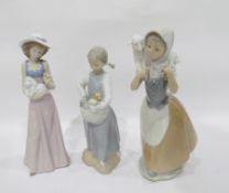 Three Nao figures of young girls, one holding a dog,