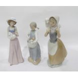 Three Nao figures of young girls, one holding a dog,