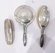Early 20th century silver-backed dressing set comprising mirror and two brushes,