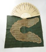 Undyed lace collar stitched onto green fabric and a carved bone and silk fan decorated with sequins,