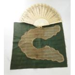 Undyed lace collar stitched onto green fabric and a carved bone and silk fan decorated with sequins,