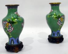 Pair of Chinese cloisonne vases, green ground decorated with flowers, on circular wooden bases,