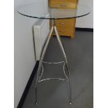 Modern circular high glass pedestal table on four metal supports united by stretchers,