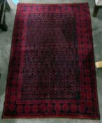 Old Beluchi rug, cherry red with allover geometric motifs to the field and stylised floral borders,