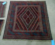 Kazak wool rug with central lozenge, having multiple hooked borders all in blue and red,