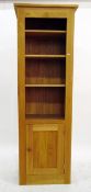 Modern lightwood bookcase cabinet having four shelves above cupboard with framed panelled door and