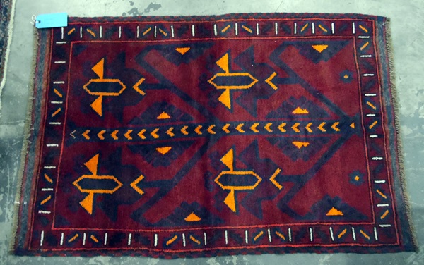 Old Baluchi wool rug with four stylised orange tulips to the red field and having stiff leaf