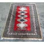 Eastern style rug, red ground with lozenge design in cream, blue and red,