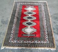 Eastern style rug, red ground with lozenge design in cream, blue and red,