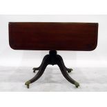 Georgian style mahogany drop-flap pedestal table on quadruped splayed reeded legs with brass paw