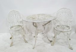 White painted cast metal circular garden table on tripod scroll supports and four matching chairs