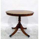 Reproduction yew wood circular table on reeded turned supports with brass claw feet and castors