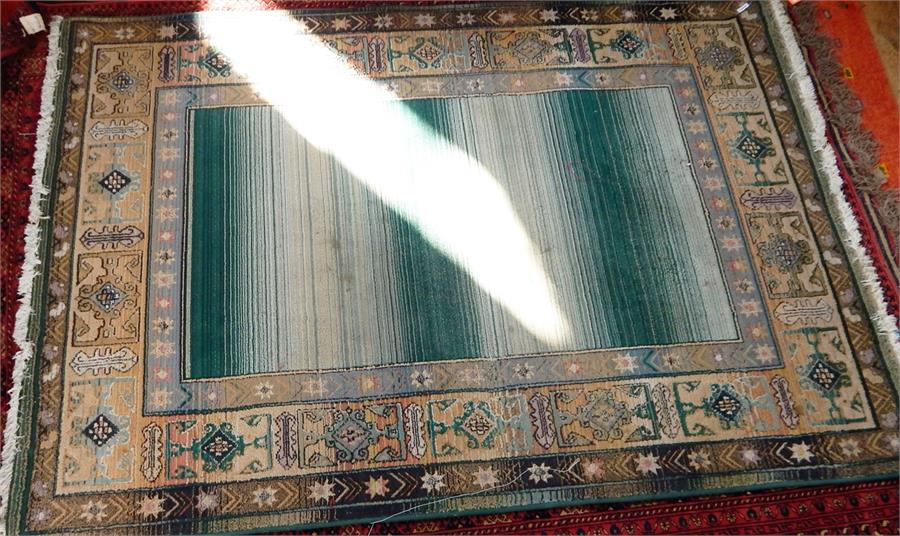 Large Oriental style rug, fringed, central panel in pale green and cream, with decorated border,