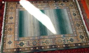 Large Oriental style rug, fringed, central panel in pale green and cream, with decorated border,