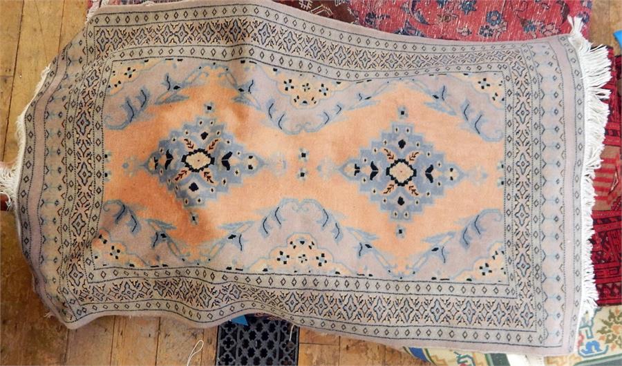 Washed Middle Eastern style rug, apricot ground with two stepped lozenge medallions, with Arabic