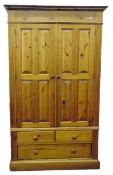 Modern pine wardrobe enclosed by two field panelled doors, over two short and one long drawer, on