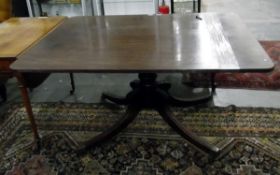 Early 19th century mahogany breakfast table on turned pedestal, four outswept supports with brass