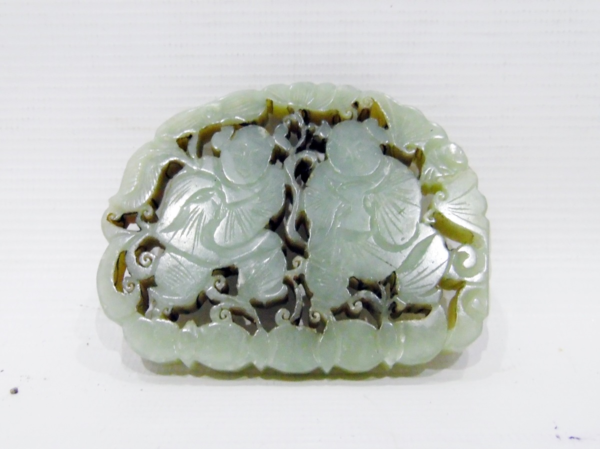 Oriental carved jade pierced tablet depicting two dancing boys, within scroll border, 8cm wide
