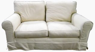 Two seater settee upholstered in cream coloured linen with loose cushions