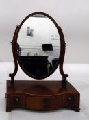 19th century mahogany oval toilet mirror, the serpentine-shaped box base fitted three drawers and on
