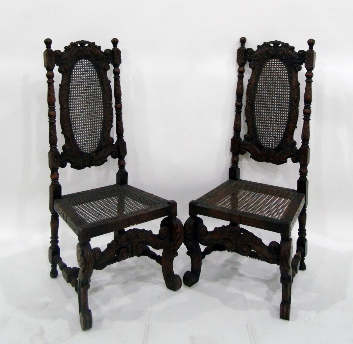 Set of four carved oak framed cane panelled dining chairs, shaped and carved stretcher and