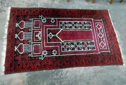 A Persian style rug, red ground with black geometric border, 91 cm x 153 cm
