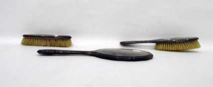 A three piece matched silver dressing set comprising mirror and two brushes, differing hallmarks,