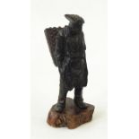 Bronzed figure of a man carrying wicker basket, standing (possibly missing pipe), on a wooden plinth