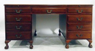 Mahogany kneehole desk having tooled leather inset top over an arrangement of nine drawers, each