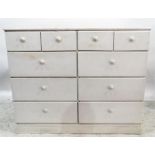 White painted pine chest of four short and six long drawers with knob handles, raised on a plinth