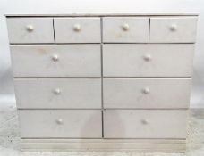 White painted pine chest of four short and six long drawers with knob handles, raised on a plinth