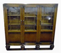 Early 20th century oak three-door bookcase standing on three stout turned supports and plinth