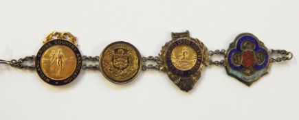 Bracelet having four 1920's and later sporting medallions, to include 9ct gold cross country and